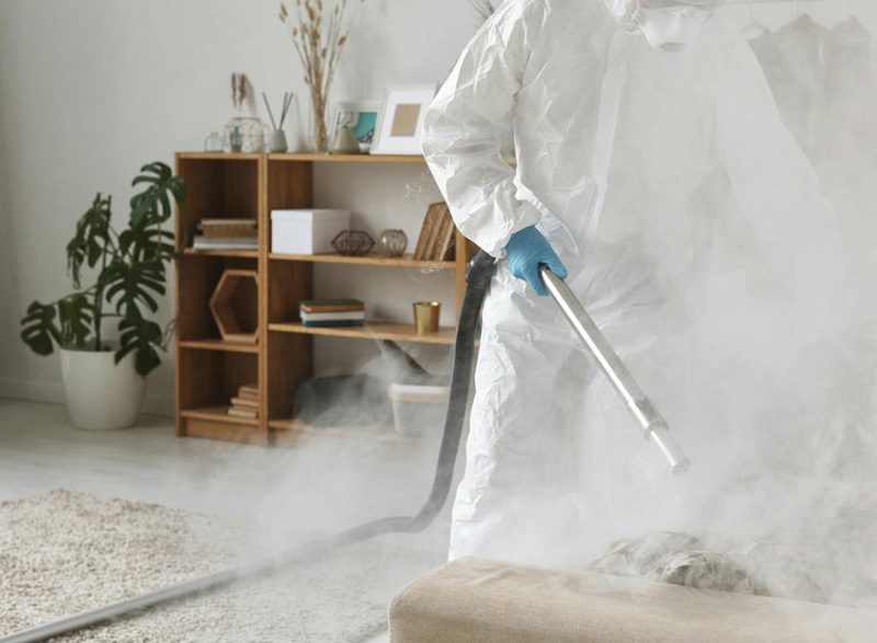 Technician in protective suit disinfecting